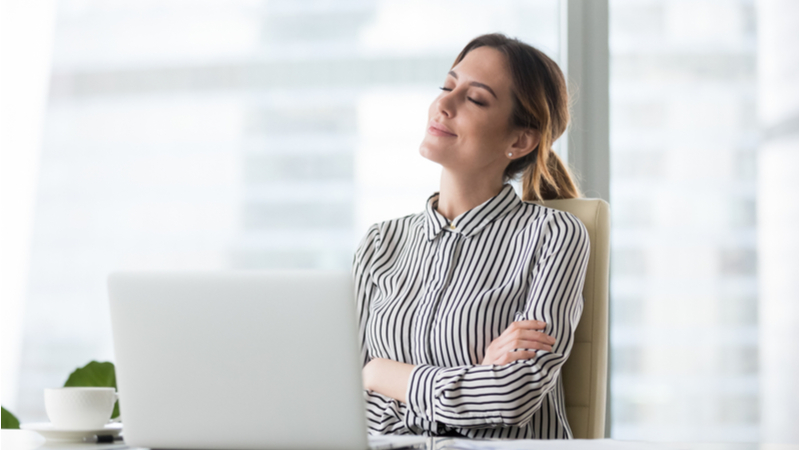 Happy woman in her office in front of laptop