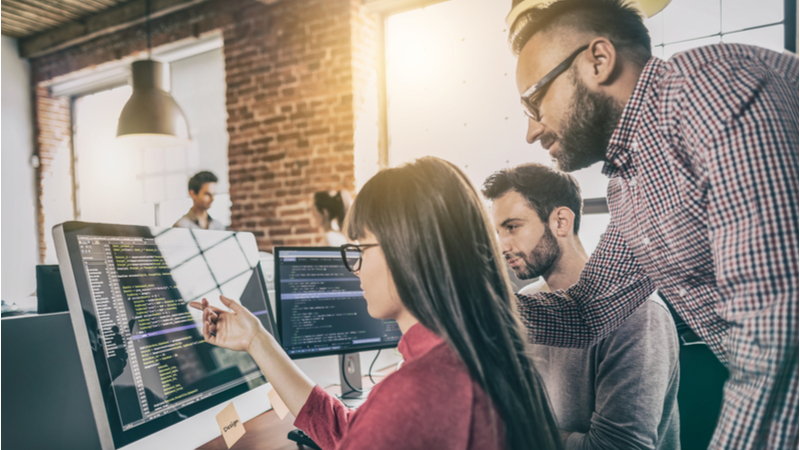 Coworkers in office discussing issues on computer screen