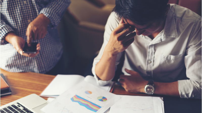 Stressed business man looking at data sheets