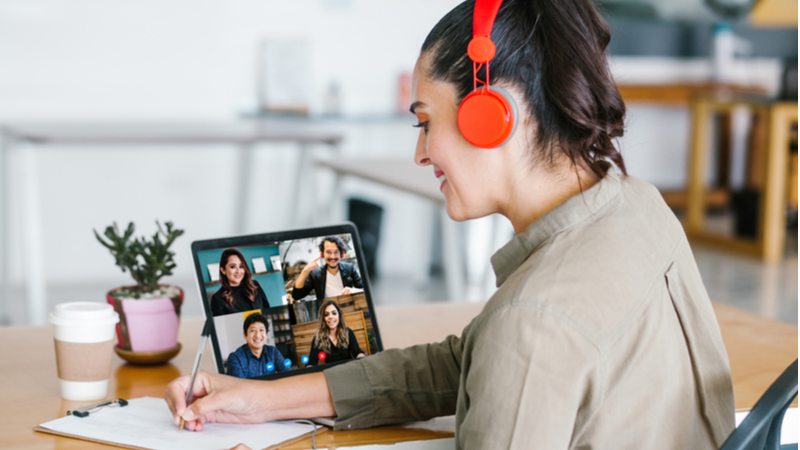 Woman talking notes during an online conference call