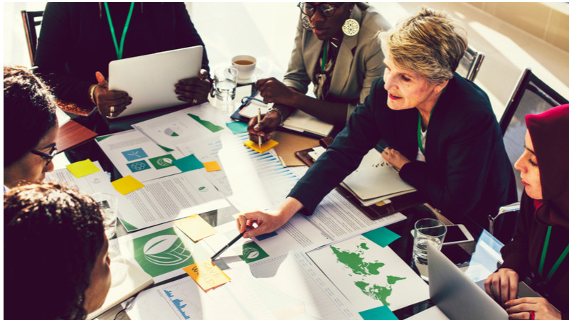 Middle-aged woman leading business meeting with documents on table